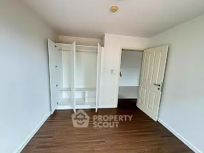 Spacious bedroom with open closet and wooden flooring in modern apartment.