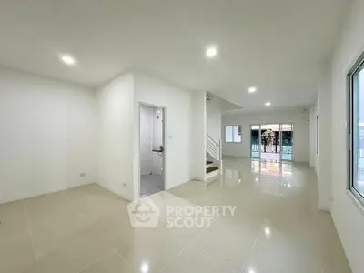 Spacious modern living room with glossy tiled floors and bright lighting, perfect for family gatherings.