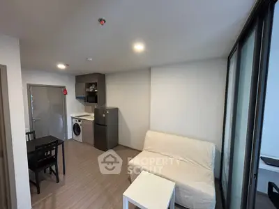 Modern apartment interior with compact living space, featuring a washing machine and sleek kitchen appliances.