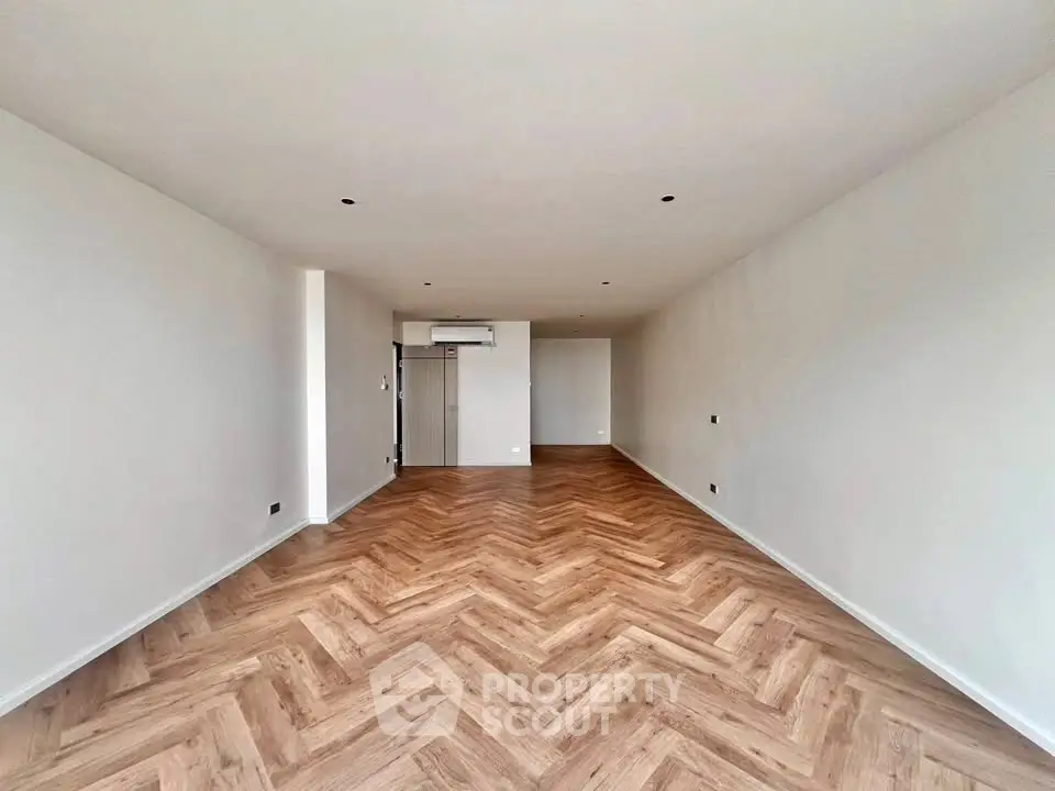 Spacious empty living room with elegant herringbone wooden flooring