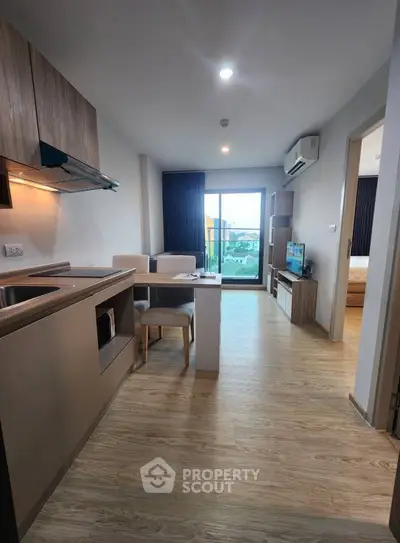Modern open-plan living room with kitchen and balcony view in stylish apartment.
