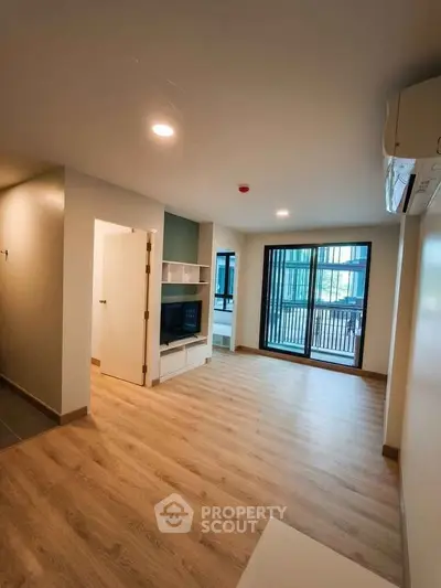 Modern living room with wooden flooring and balcony access in a stylish apartment.
