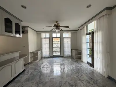 Spacious living room with marble flooring and large windows for natural light.