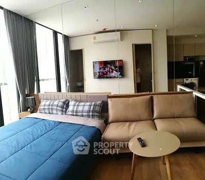 Modern studio apartment with cozy bed and stylish sofa in open layout.