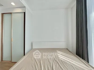 Minimalist bedroom with sleek sliding closet doors and large window with curtains.
