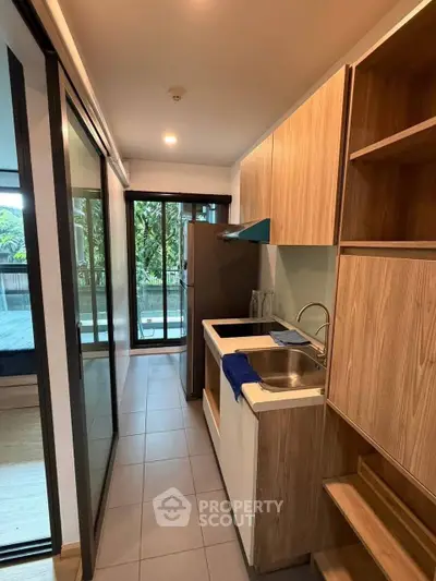 Modern compact kitchen with sleek design and large windows overlooking greenery.
