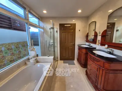 Luxurious bathroom with elegant wooden vanities and a spacious bathtub, perfect for relaxation.