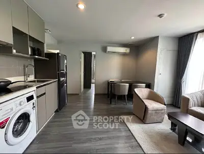 Modern living room with open kitchen, featuring sleek appliances and stylish furniture in a cozy apartment.