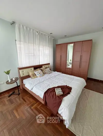 Spacious bedroom with elegant wooden flooring and modern wardrobe