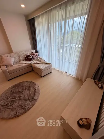 Cozy living room with large windows and stylish decor, offering a serene view.