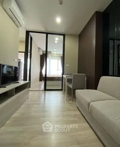 Modern living room with sleek furniture and sliding glass doors leading to a bright bedroom.