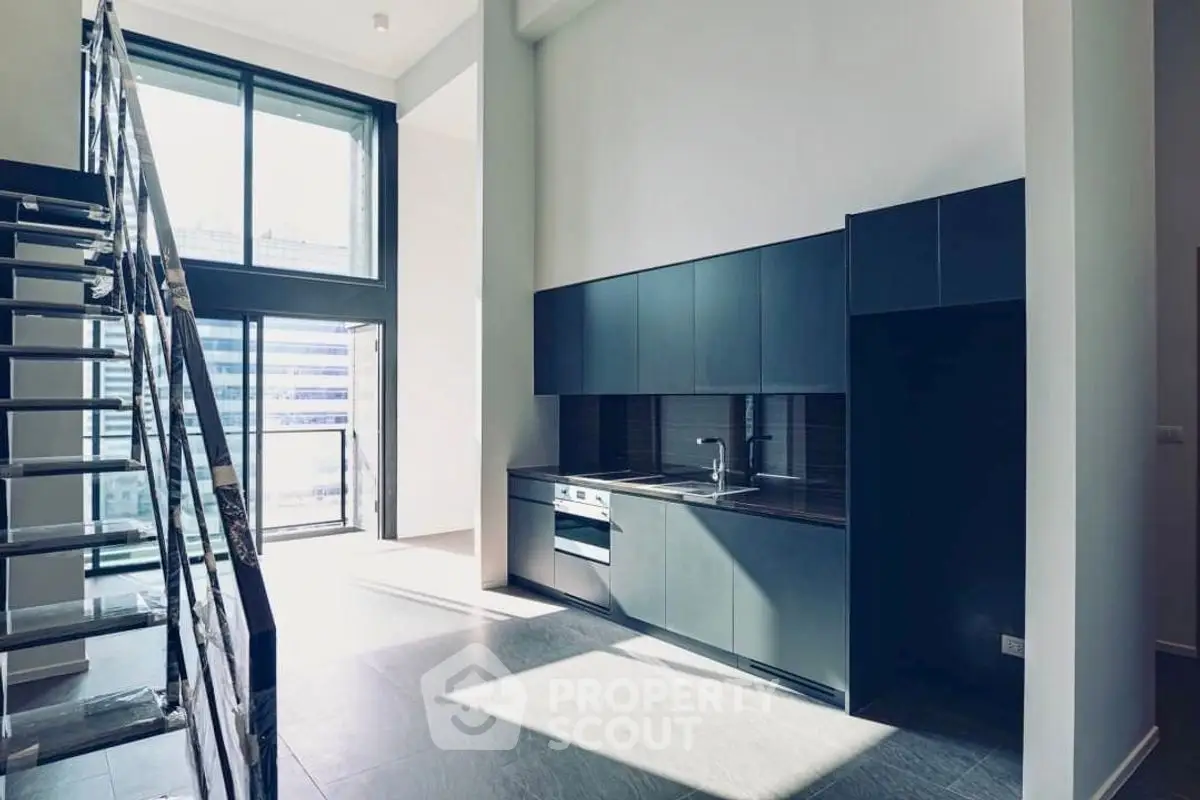Modern loft apartment with sleek kitchen and large windows offering abundant natural light.