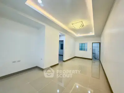 Spacious modern living room with elegant ceiling lighting and glossy tiled floors.