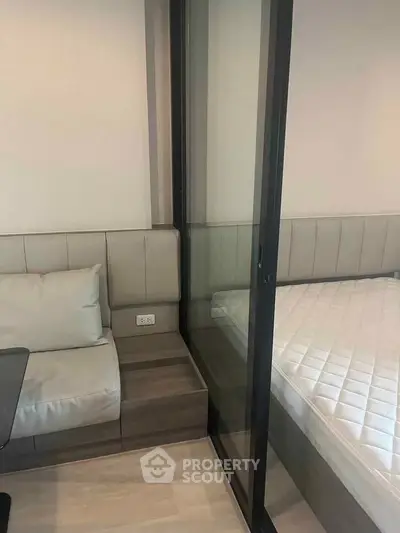 Modern compact bedroom with glass partition and cozy seating area