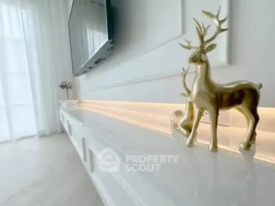 Elegant living room with modern decor and mounted TV, featuring stylish gold deer sculptures.