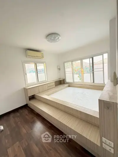 Spacious bedroom with elevated platform bed and large windows for natural light.