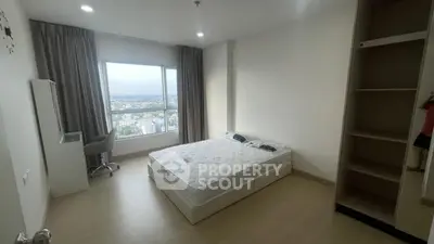 Spacious bedroom with large window offering stunning city view and modern furnishings.