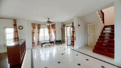 Spacious living room with elegant staircase and large windows, perfect for family gatherings.