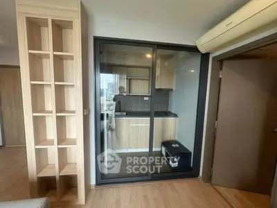 Modern apartment with compact closed kitchen and wooden shelving unit.