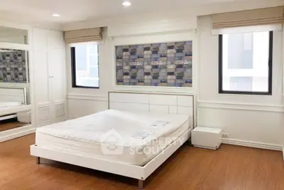 Spacious bedroom with modern decor and large windows in a stylish apartment.