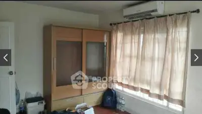 Cozy bedroom with wardrobe and air conditioning, featuring natural light through curtained windows.