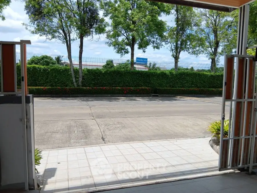 Open garage view with lush greenery and street access, ideal for easy commuting.