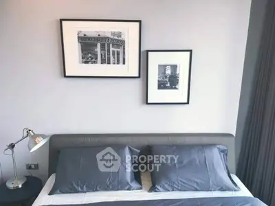 Modern bedroom with stylish decor and framed art above a sleek gray bed.