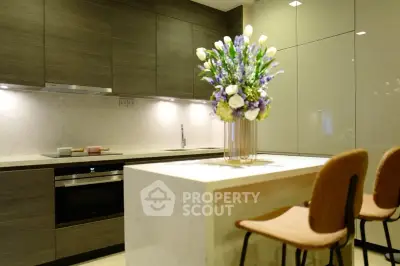 Modern kitchen with sleek cabinetry and elegant island seating, featuring a stylish floral centerpiece.