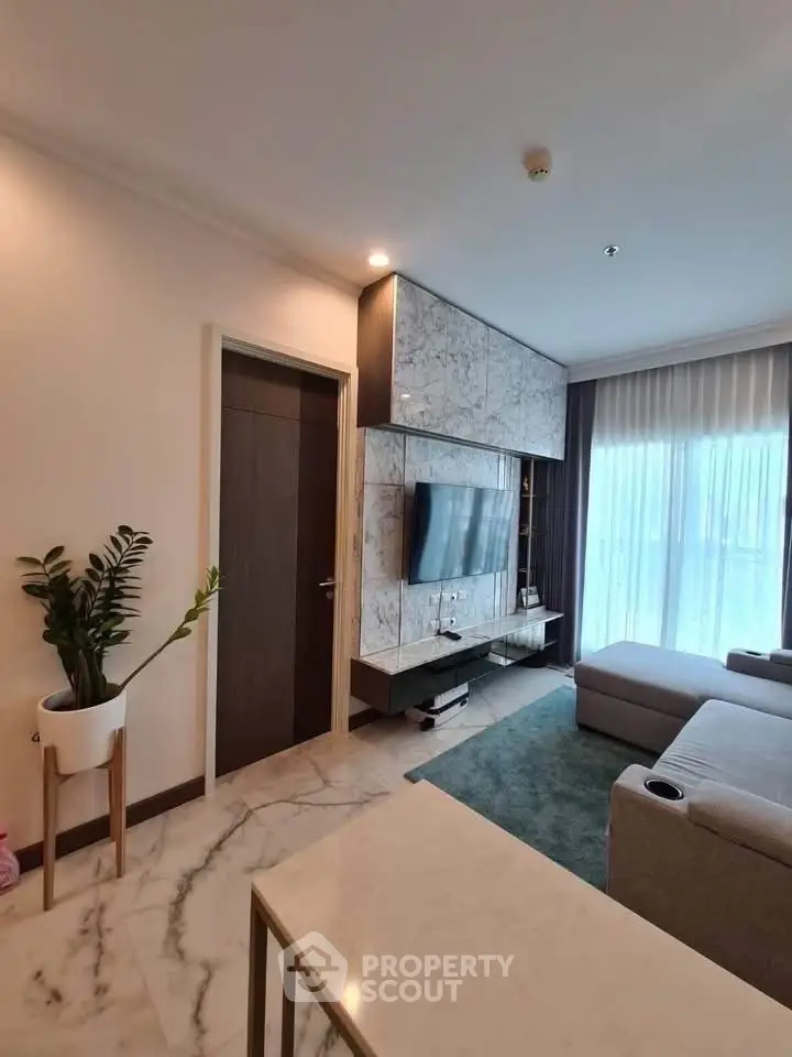 Modern living room with marble accents and large TV, featuring a cozy sectional sofa and elegant decor.