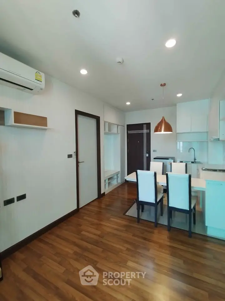 Modern open-plan living and dining area with wooden flooring and stylish lighting.