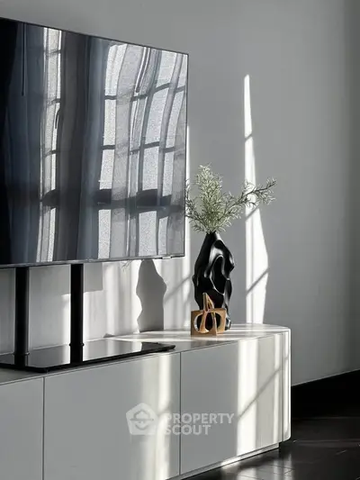 Modern living room with sleek TV stand and stylish decor, bathed in natural light.