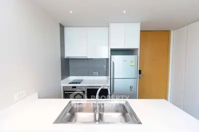 Modern kitchen with sleek white cabinets and stainless steel appliances in a contemporary apartment.