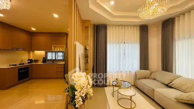 Luxurious open-layout living room with modern kitchen, elegant chandelier, and cozy seating area.