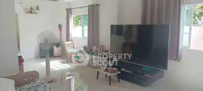 Spacious living room with large TV and natural light