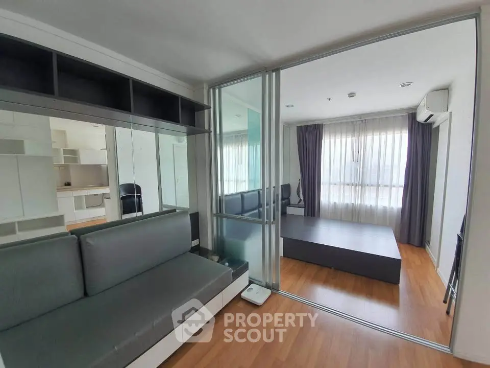 Modern apartment interior with glass partition, wooden flooring, and natural light.