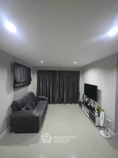 Modern living room with sleek gray sofa and large TV, perfect for relaxation and entertainment.