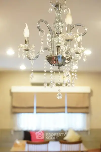 Elegant chandelier in a stylish living room with cozy seating and ambient lighting.
