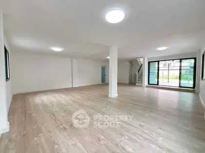 Spacious open-plan living area with large windows and wooden flooring