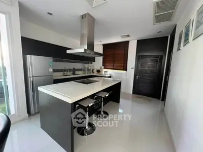 Modern kitchen with sleek design, island counter, and stainless steel appliances in a stylish home.