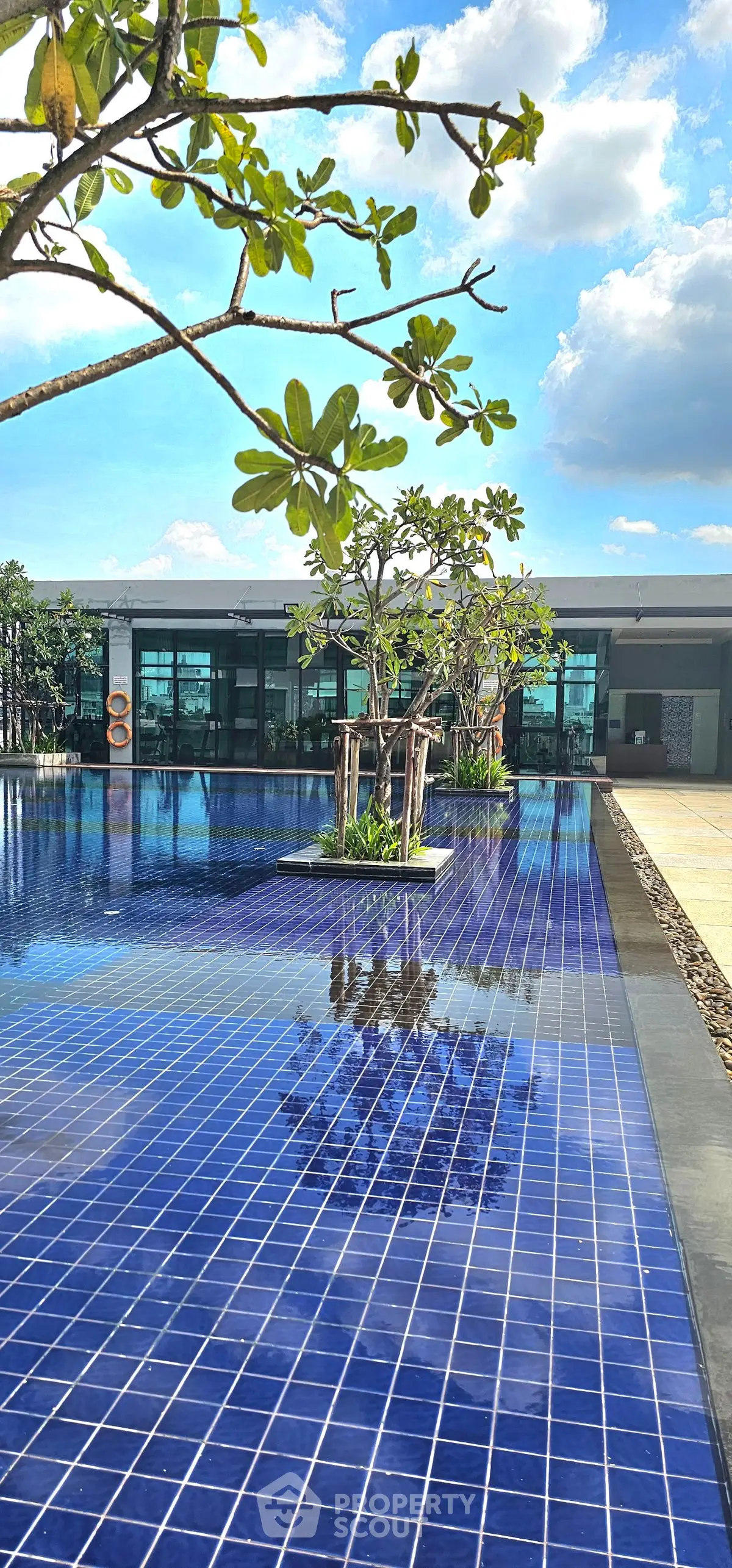 Luxurious outdoor pool area with blue tiles and lush greenery, perfect for relaxation and leisure.