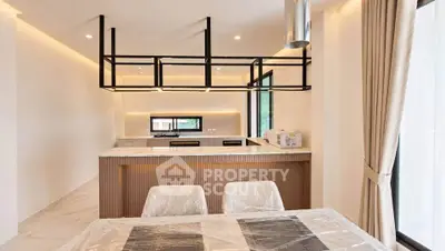 Modern kitchen with open layout and sleek design, featuring a dining area and large windows.
