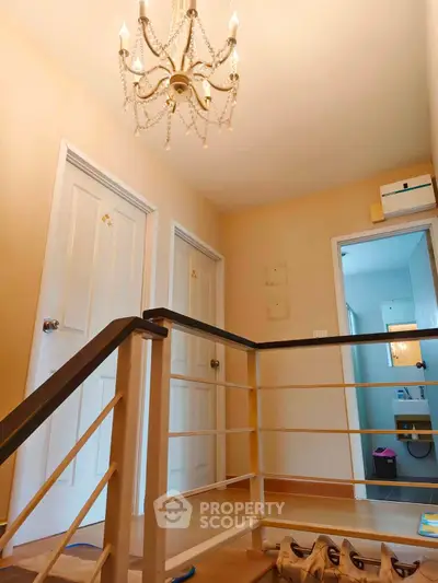 Charming interior hallway with elegant chandelier and staircase, showcasing a cozy residential ambiance.