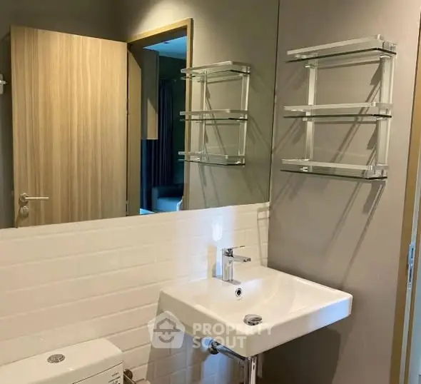 Modern bathroom with sleek sink and wall-mounted shelves in a stylish apartment.