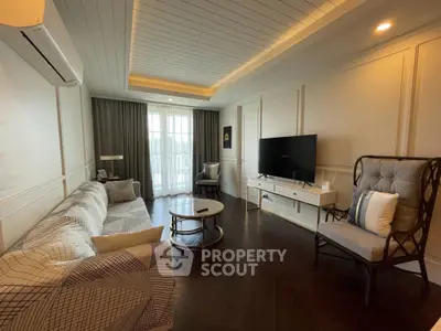 Elegant living room with modern decor, featuring a cozy sofa, stylish armchair, and large flat-screen TV.