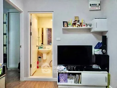 Modern living room with TV unit and view into a compact bathroom, showcasing efficient space utilization.