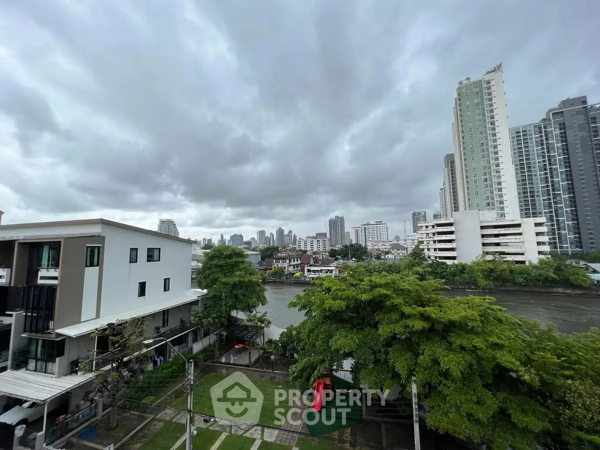Stunning cityscape view from a high-rise balcony overlooking a river and lush greenery.