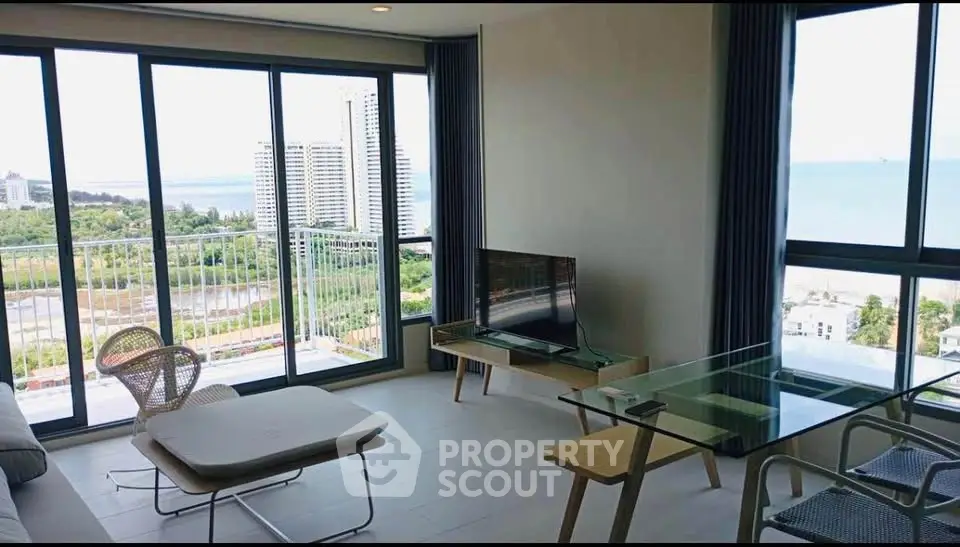 Modern living room with stunning ocean view and floor-to-ceiling windows in a high-rise apartment.