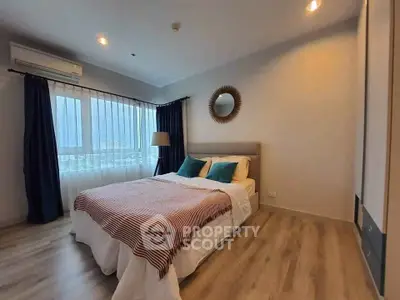 Cozy bedroom with modern decor and large window offering natural light.