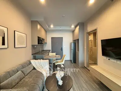 Modern living room with open kitchen, cozy sofa, and stylish decor in a contemporary apartment.