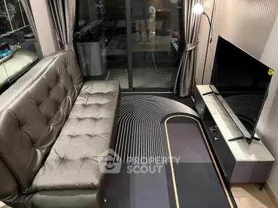 Modern living room with sleek sofa and flat-screen TV, featuring stylish decor and large window.